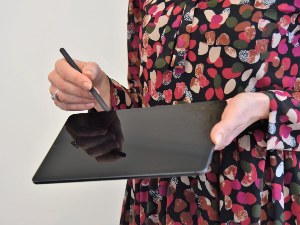 Una donna porge un tablet spento e il pennino, per permettere la lettura del documento e la firma grafometrica conseguente.