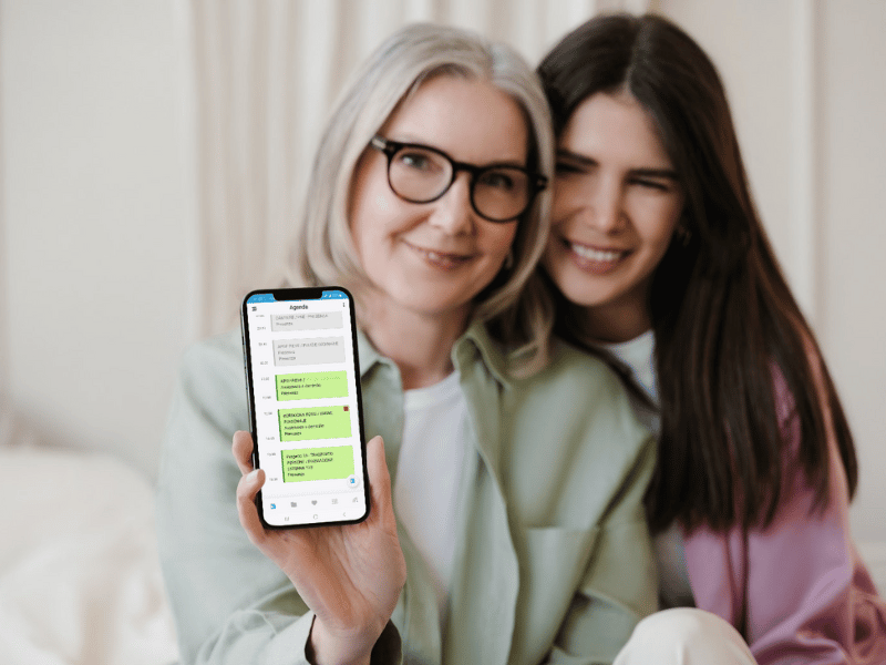 Due donne, una giovane e una vecchia, mostrano su uno smartphone l'agenda dell'app Sistema381.